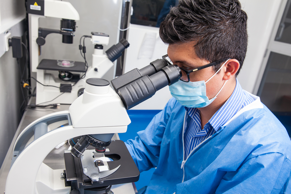 Young male scientist looking at slides under a microscope