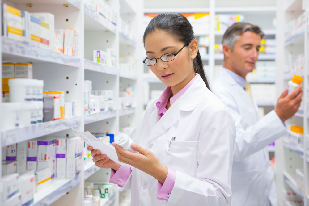 Female pharmacist reading the label on a medicine pot